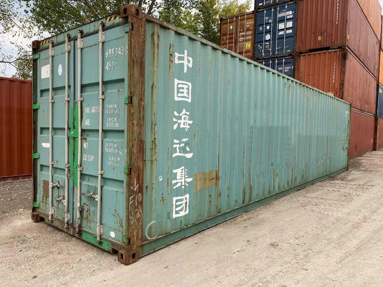 Used shipping container with faded paint, rust, and shipping-line markings